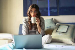 Woman sitting on bed using laptop