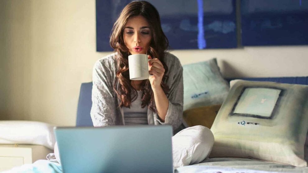 Woman sitting on bed using laptop