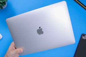 MacBook being held against blue background